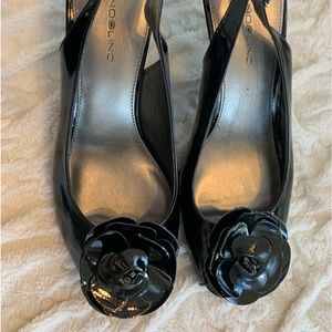 Bandalino black heels with strap, and decorative flower attached.